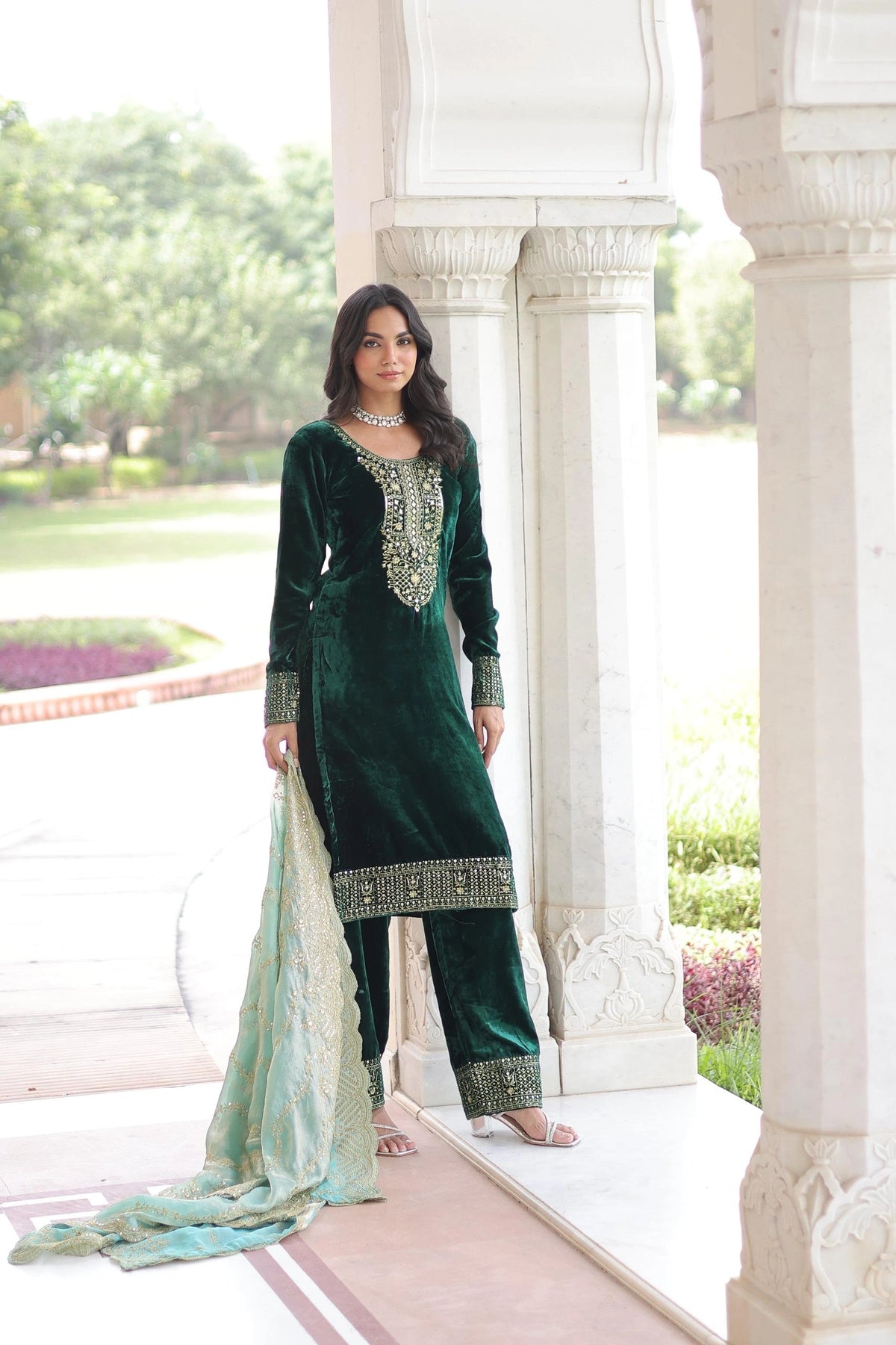 Woman wearing a deep blue embroidered kurta set with detailed neckline work and a soft organza dupatta with gold borders.