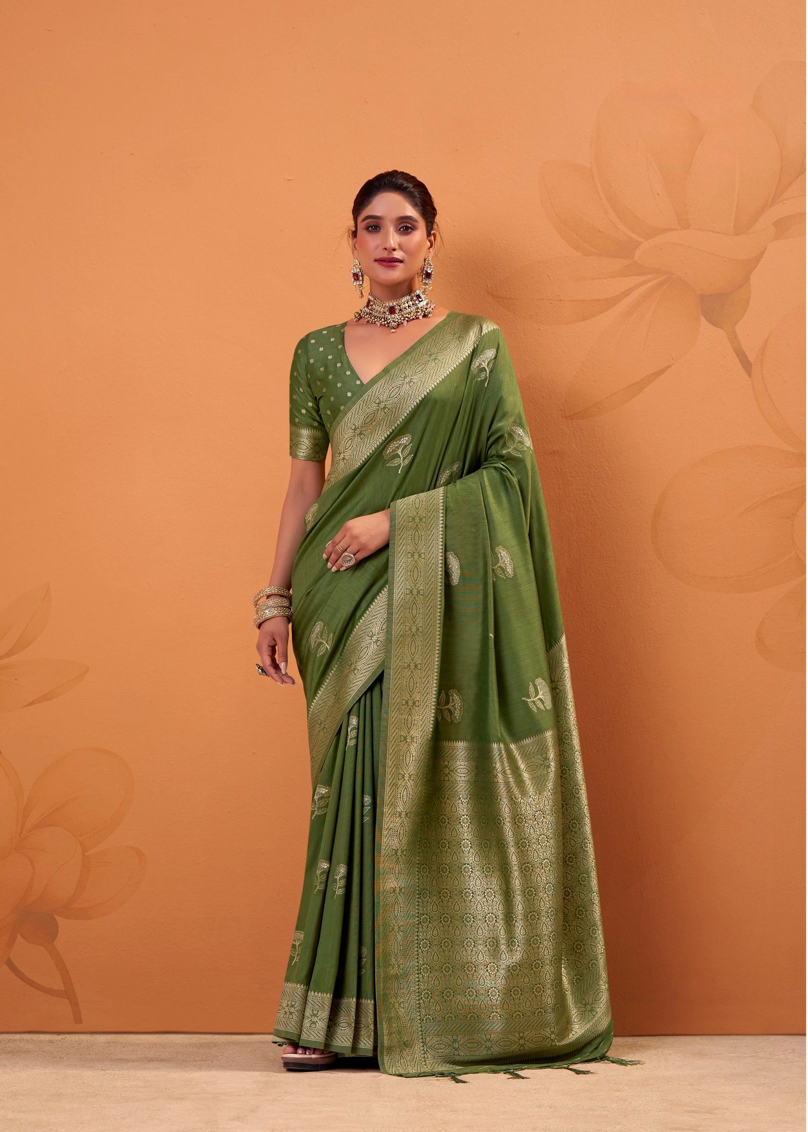 Woman wearing a green saree with a matching blouse against an orange background