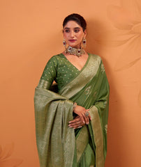 Woman wearing a green saree with a matching blouse against an orange background