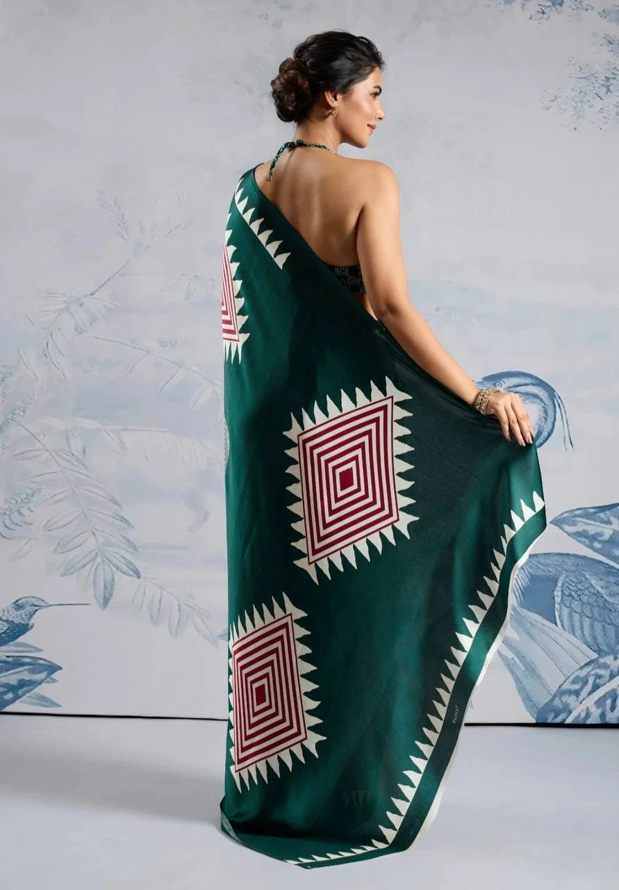 Woman wearing a green saree with red and white patterns against a light gray background