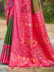 Traditional pink and green saree with intricate patterns on a natural background