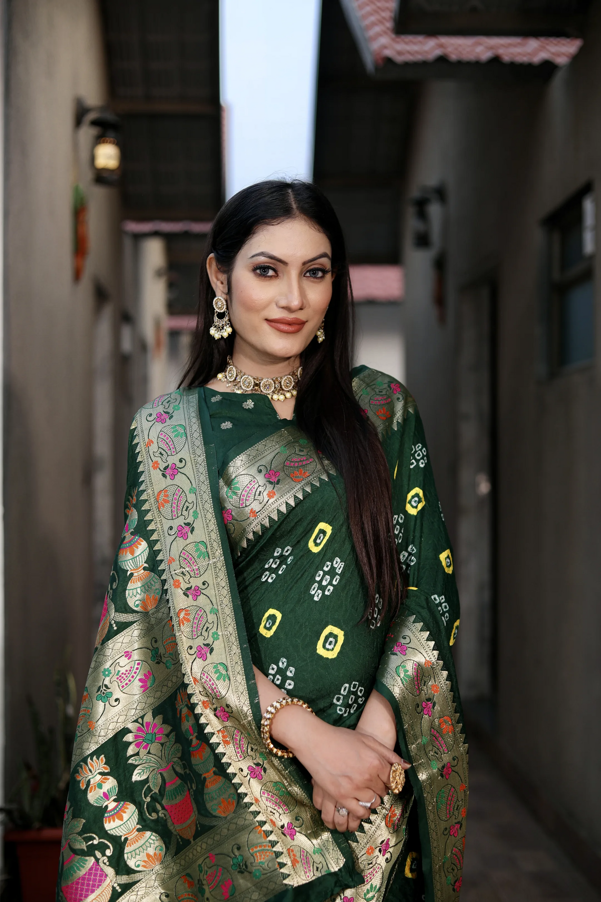 Woman wearing a traditional green embroidered saree with a blurred background