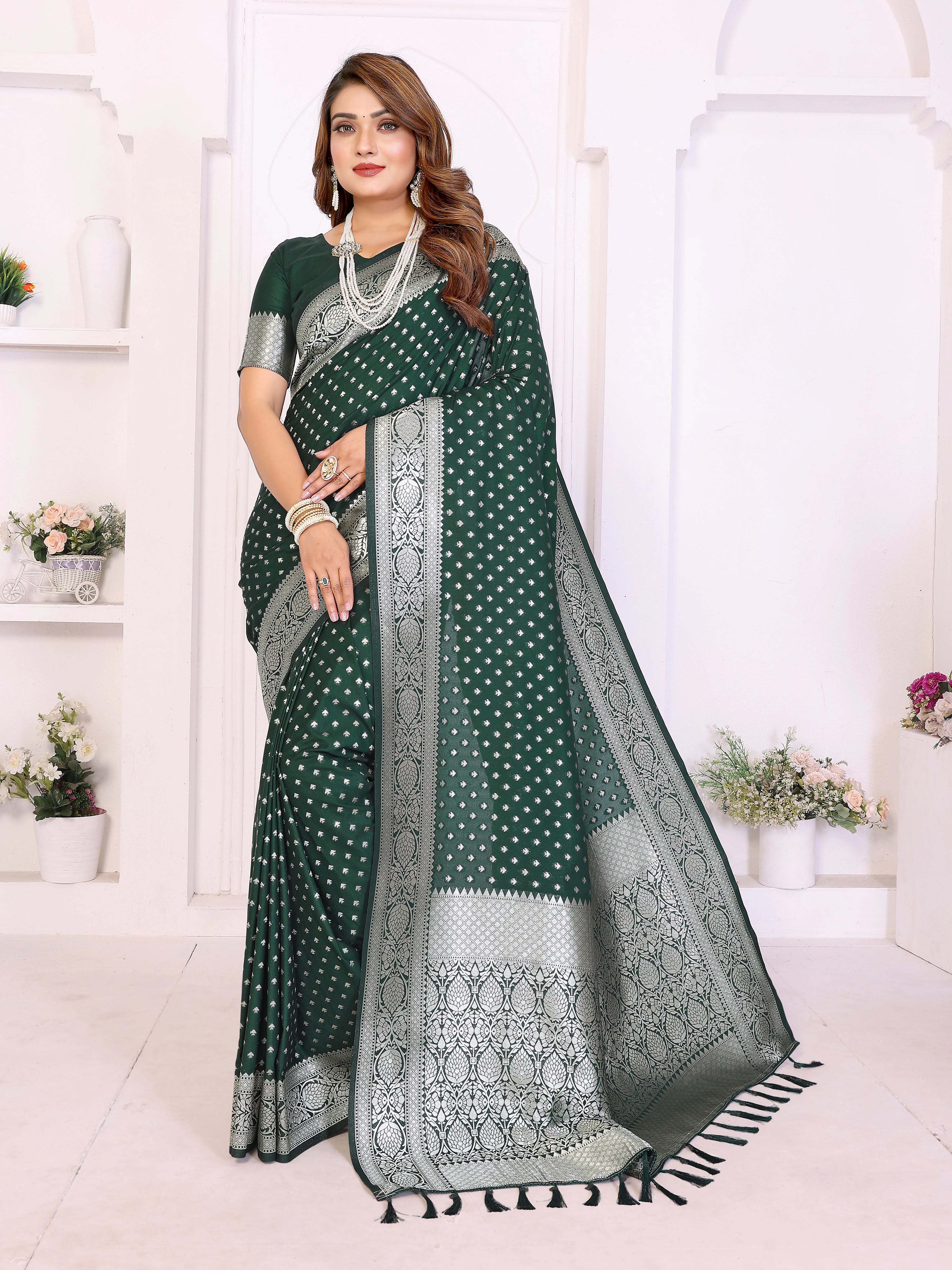 Woman wearing a green saree with white patterns in a white room.
