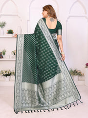 Woman holding a green saree with white patterns in a white room.
