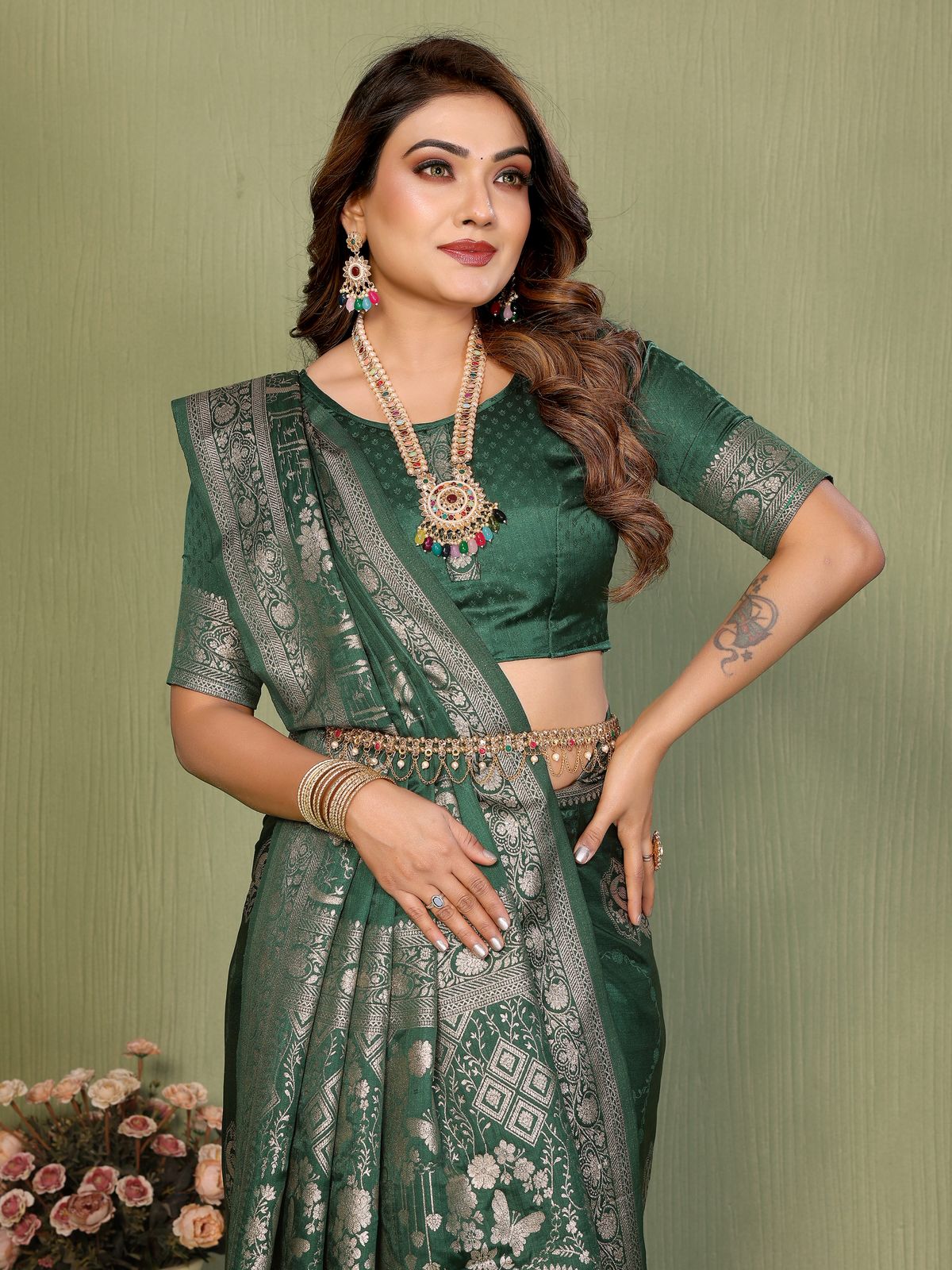 Woman wearing a green saree with intricate patterns against a green background
