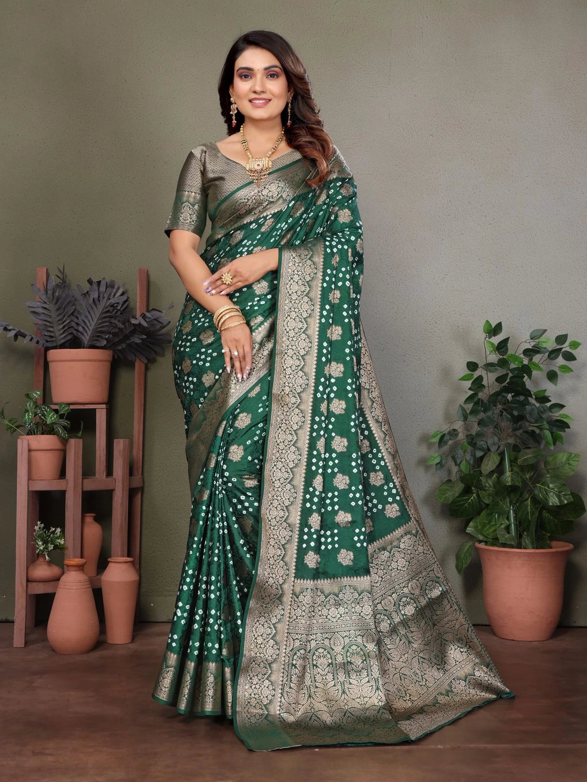 Woman wearing a green and silver saree with plants in the background