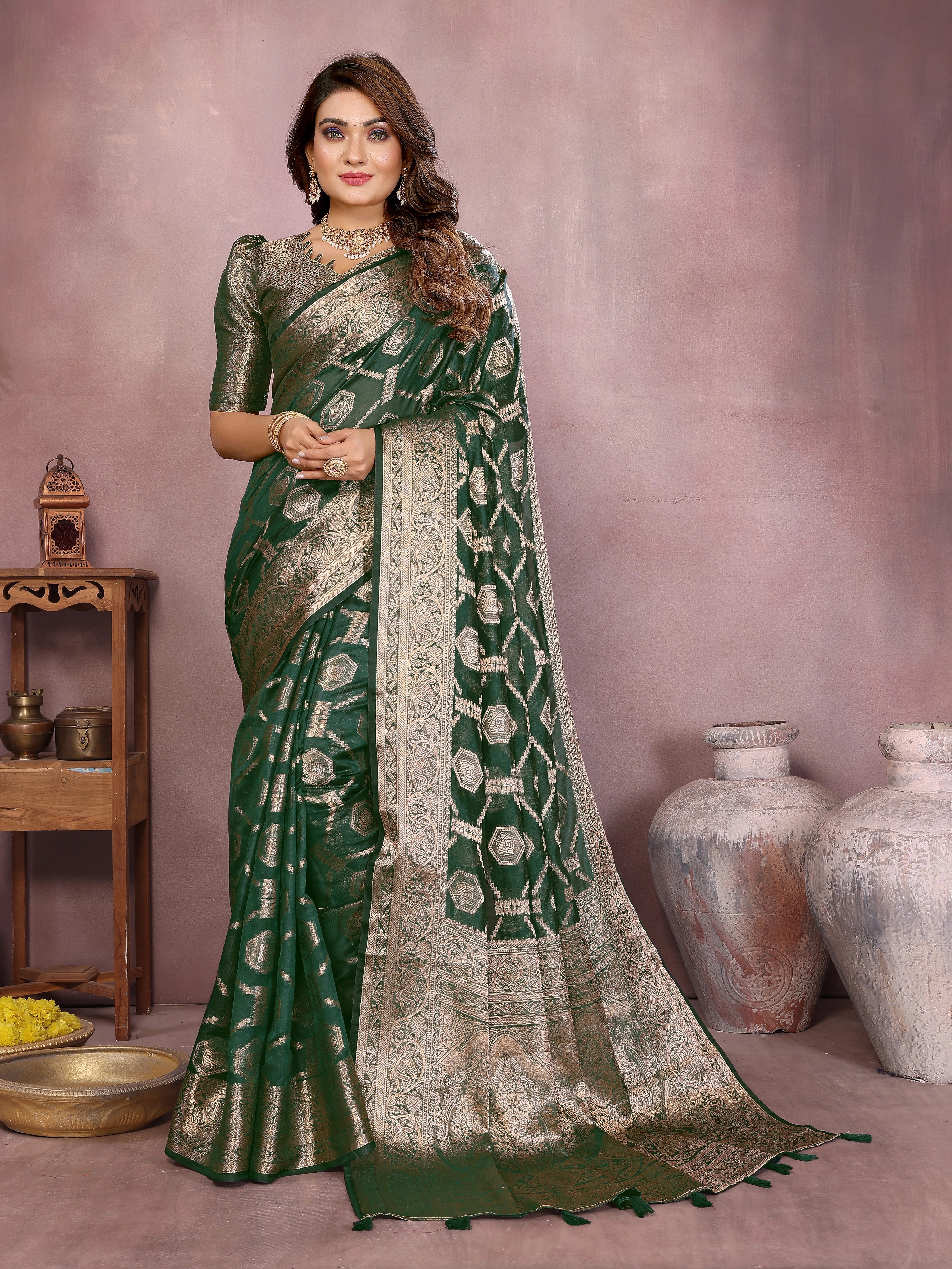 Woman wearing a green and beige saree with a patterned border against a neutral background.