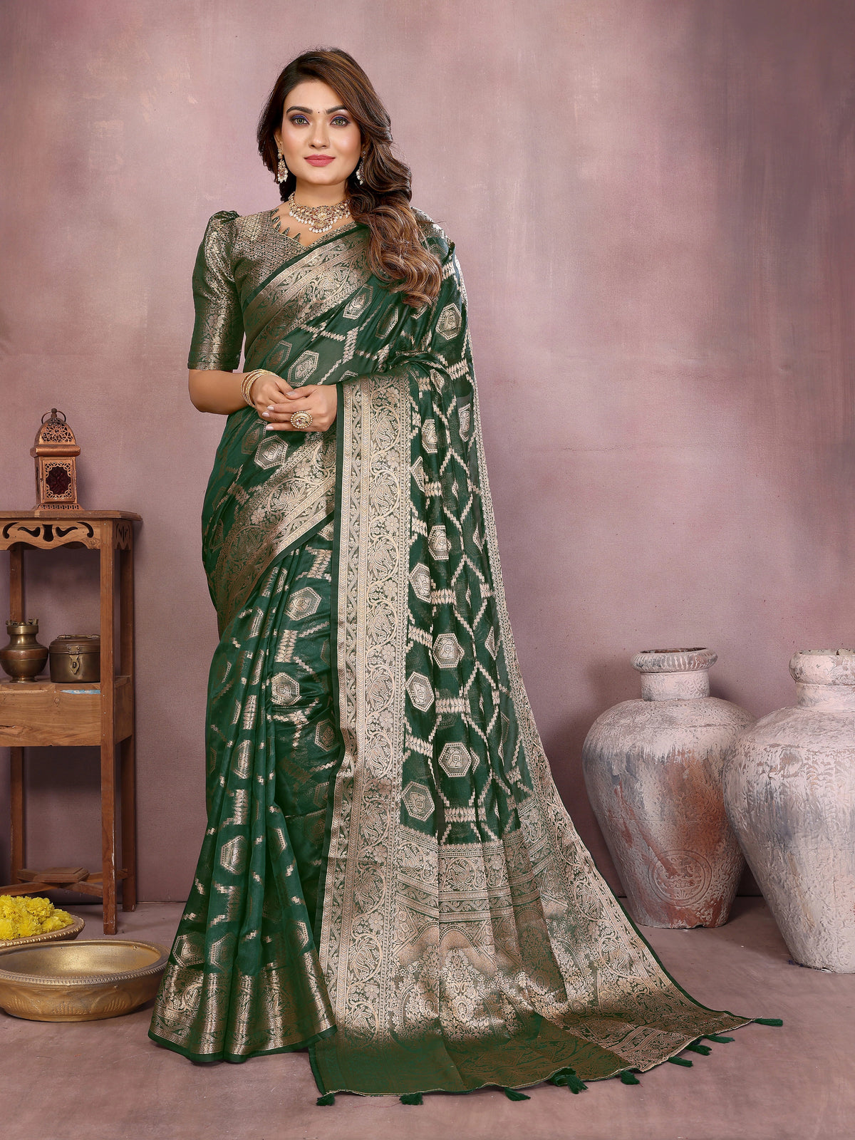 Woman wearing a green and beige saree with a patterned border against a neutral background.