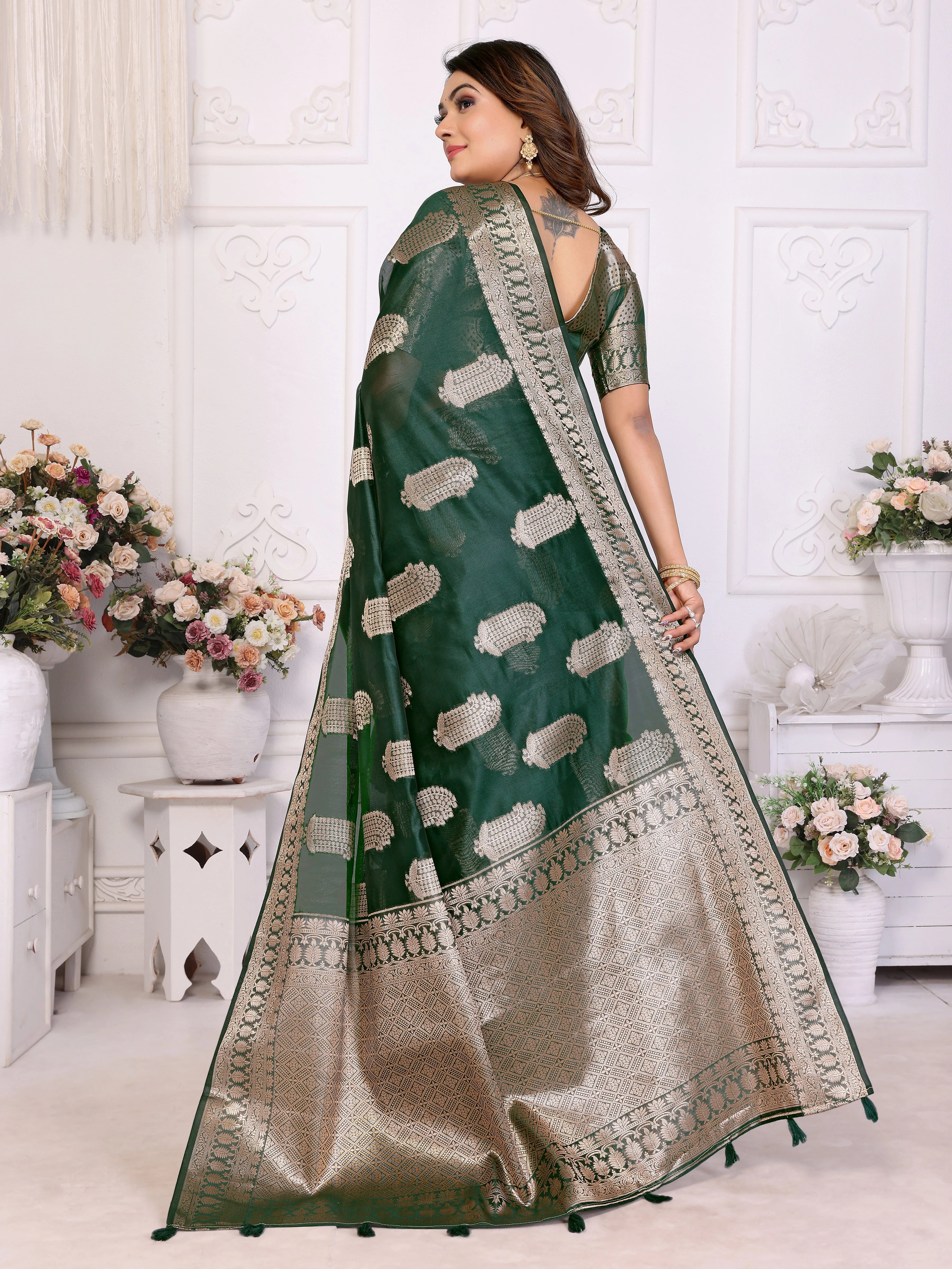 Woman wearing a green and beige saree with floral decorations in the background