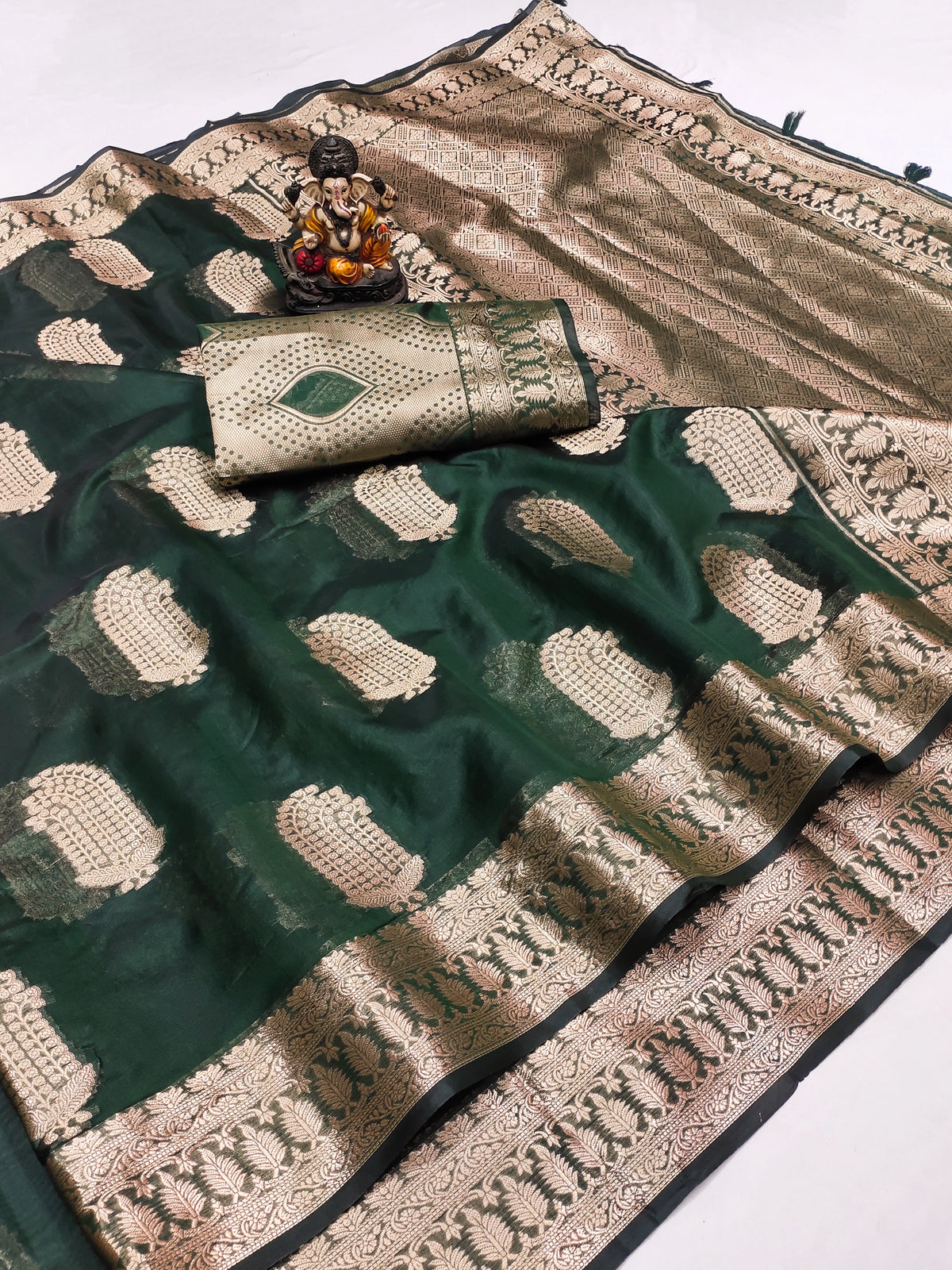 Green and beige saree with intricate patterns on a white background