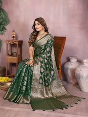 Woman in a green and silver saree sitting on a chair with a decorative background.