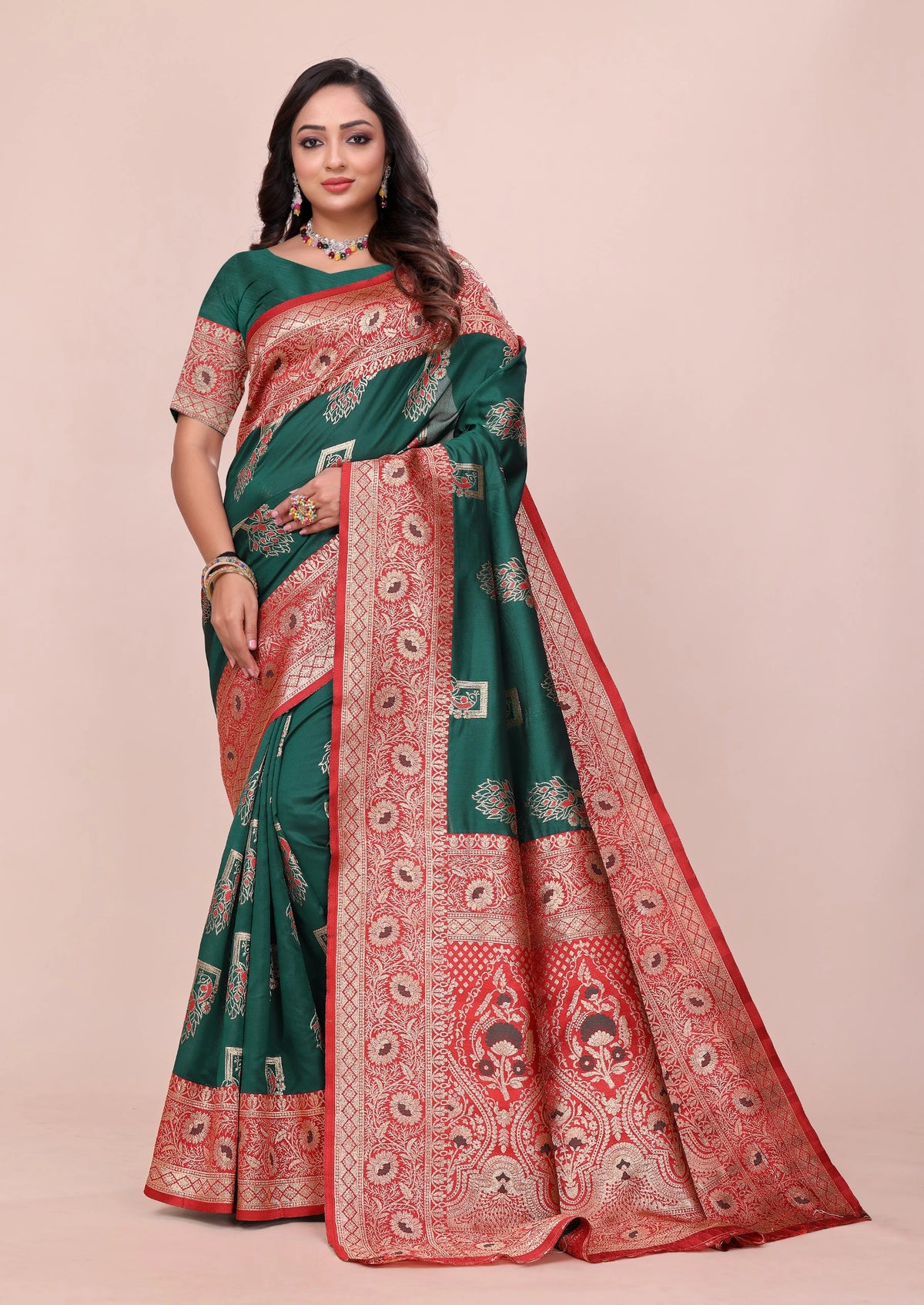 Woman wearing a green and red saree with a pattern on a beige background