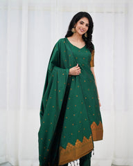 Woman wearing a green and brown traditional outfit with a white curtain background