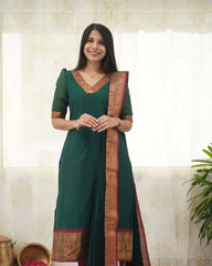 Woman wearing a green traditional outfit with a decorative border indoors.