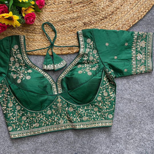 Green embroidered blouse on a textured surface with flowers in the background