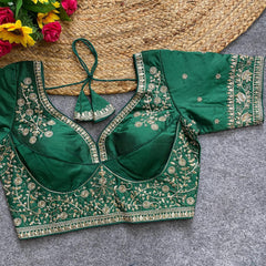 Green embroidered blouse on a textured surface with flowers in the background