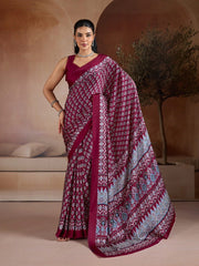 Woman wearing a maroon saree with white patterns in an indoor setting