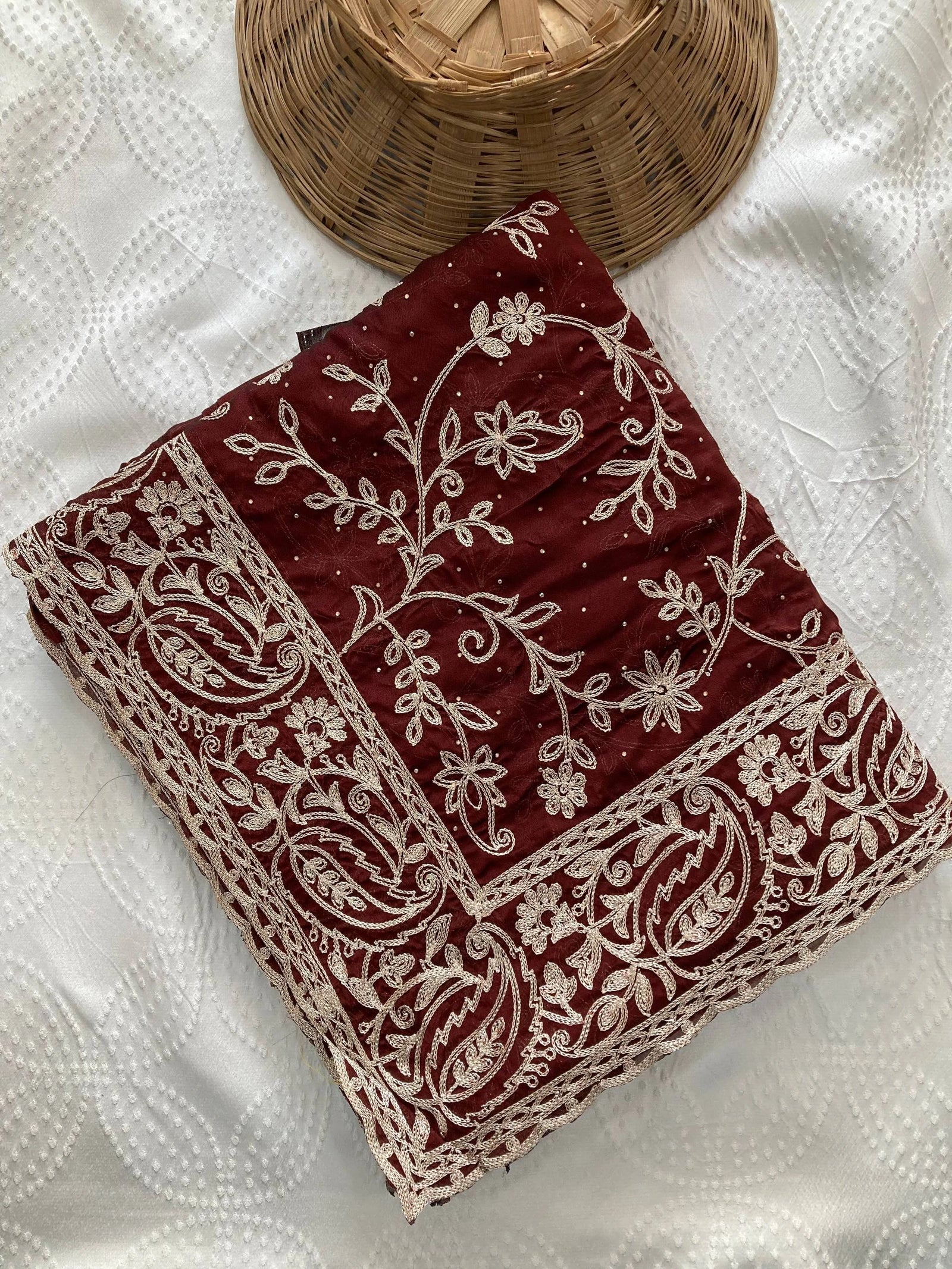 Red fabric with white embroidery on a textured white surface