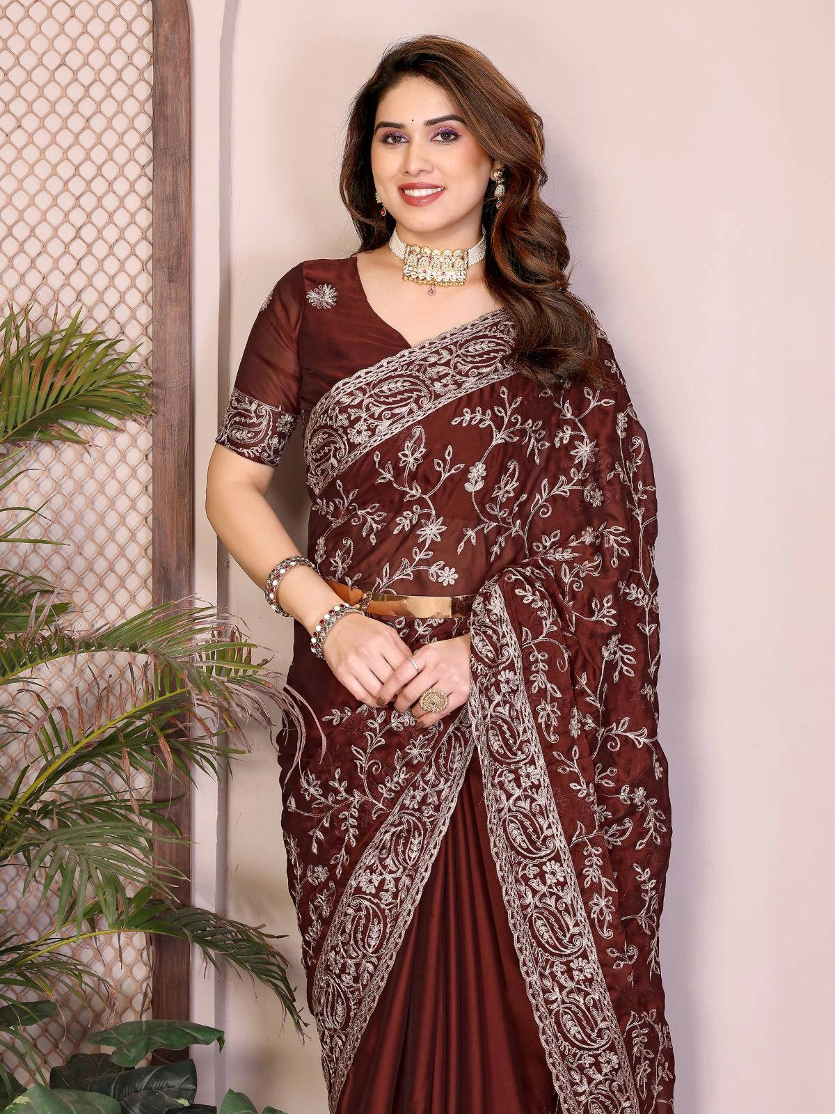 Woman wearing a maroon saree with white patterns against a neutral background