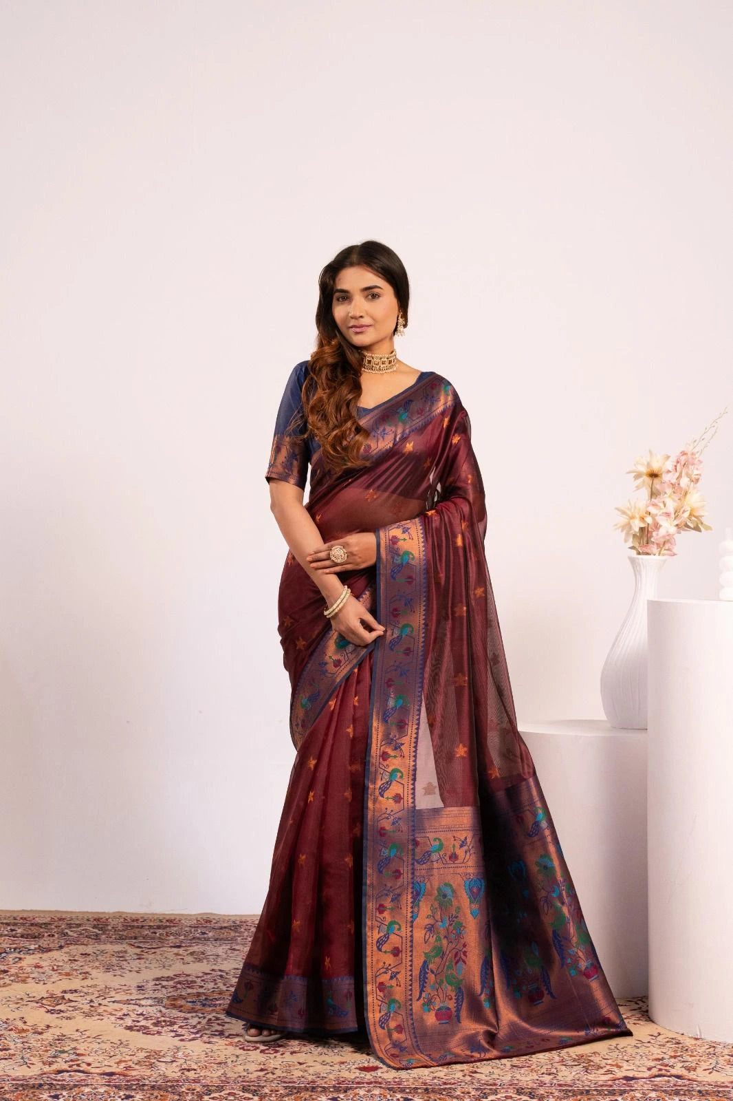Woman wearing a traditional saree with a floral pattern against a white background