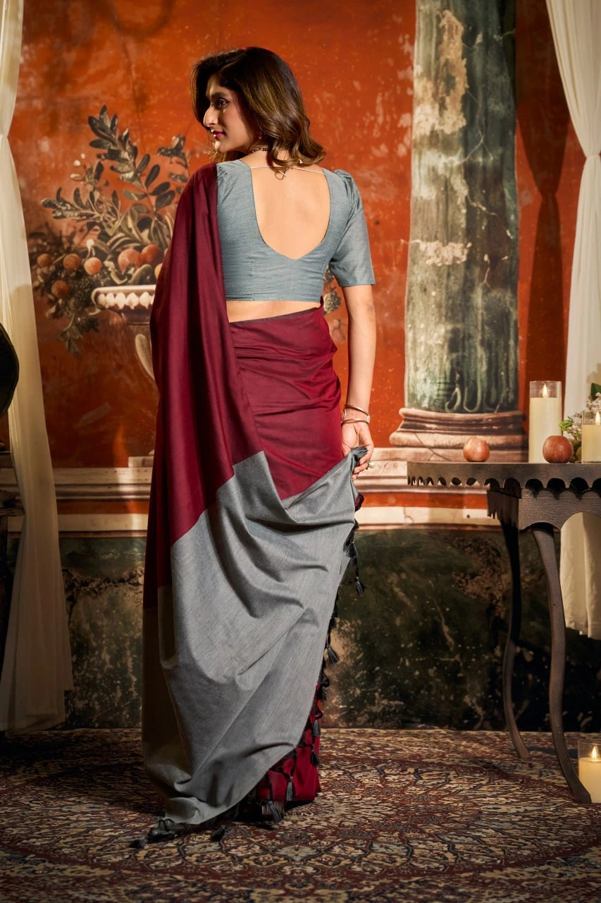 Woman in a traditional outfit with a red and gray saree in an ornate room.