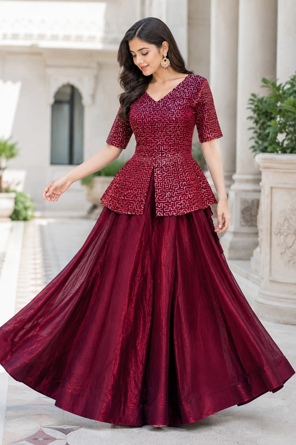 Woman wearing a maroon traditional outfit with a peplum top and long skirt in front of classical architecture.