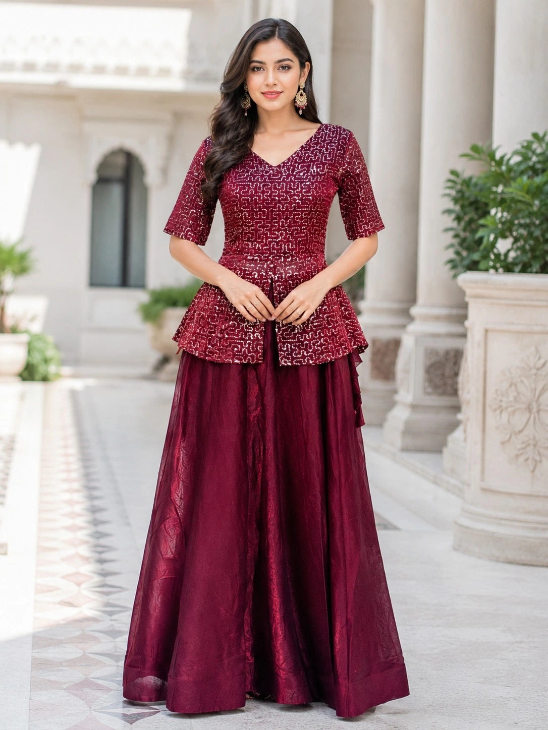 Woman wearing a maroon traditional outfit with a white architectural background