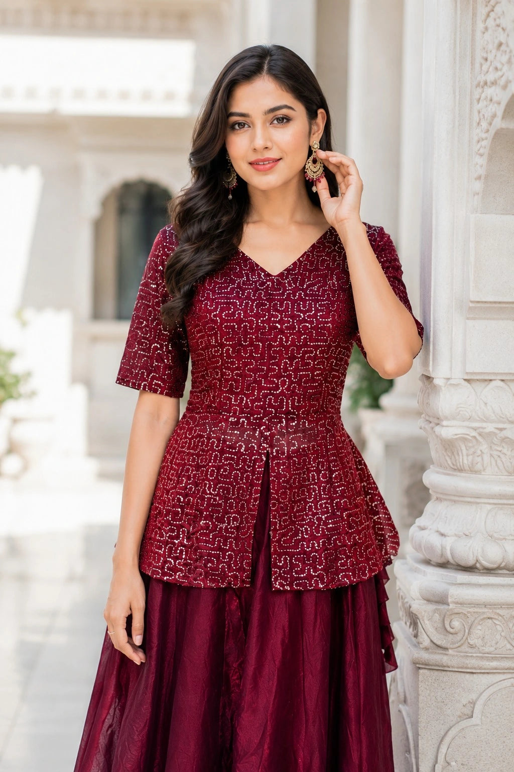 Woman wearing a maroon patterned dress standing against an architectural background