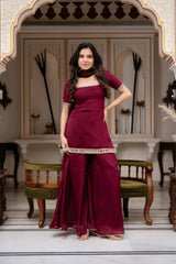Woman in a maroon traditional outfit standing in an ornate room.