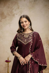 Woman wearing a maroon embroidered traditional outfit against a beige background
