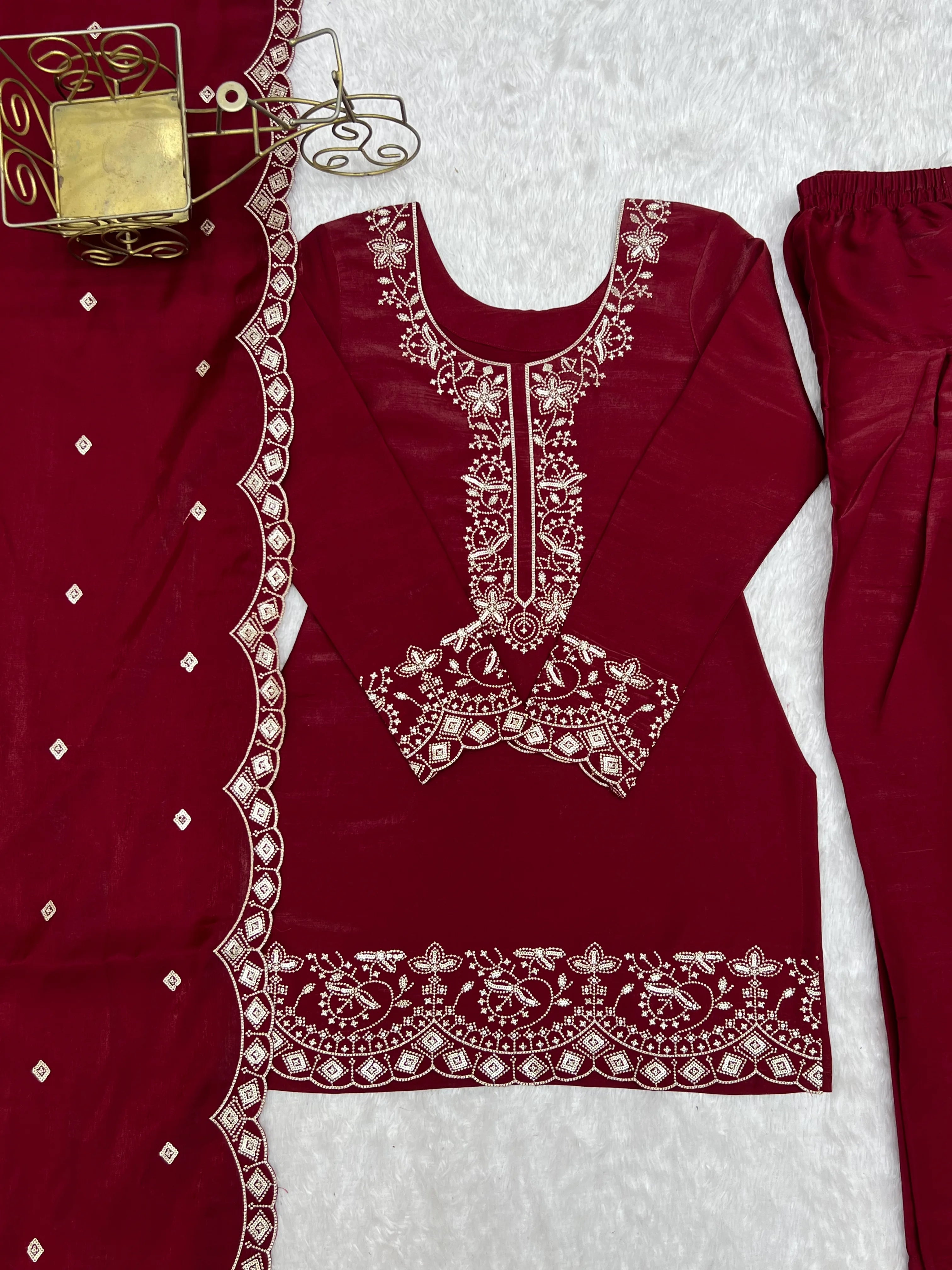 Maroon embroidered outfit with white pants on a light gray background