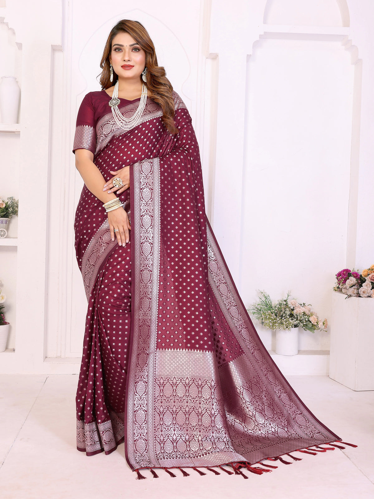 Woman wearing a maroon saree with white patterns in a bright room.