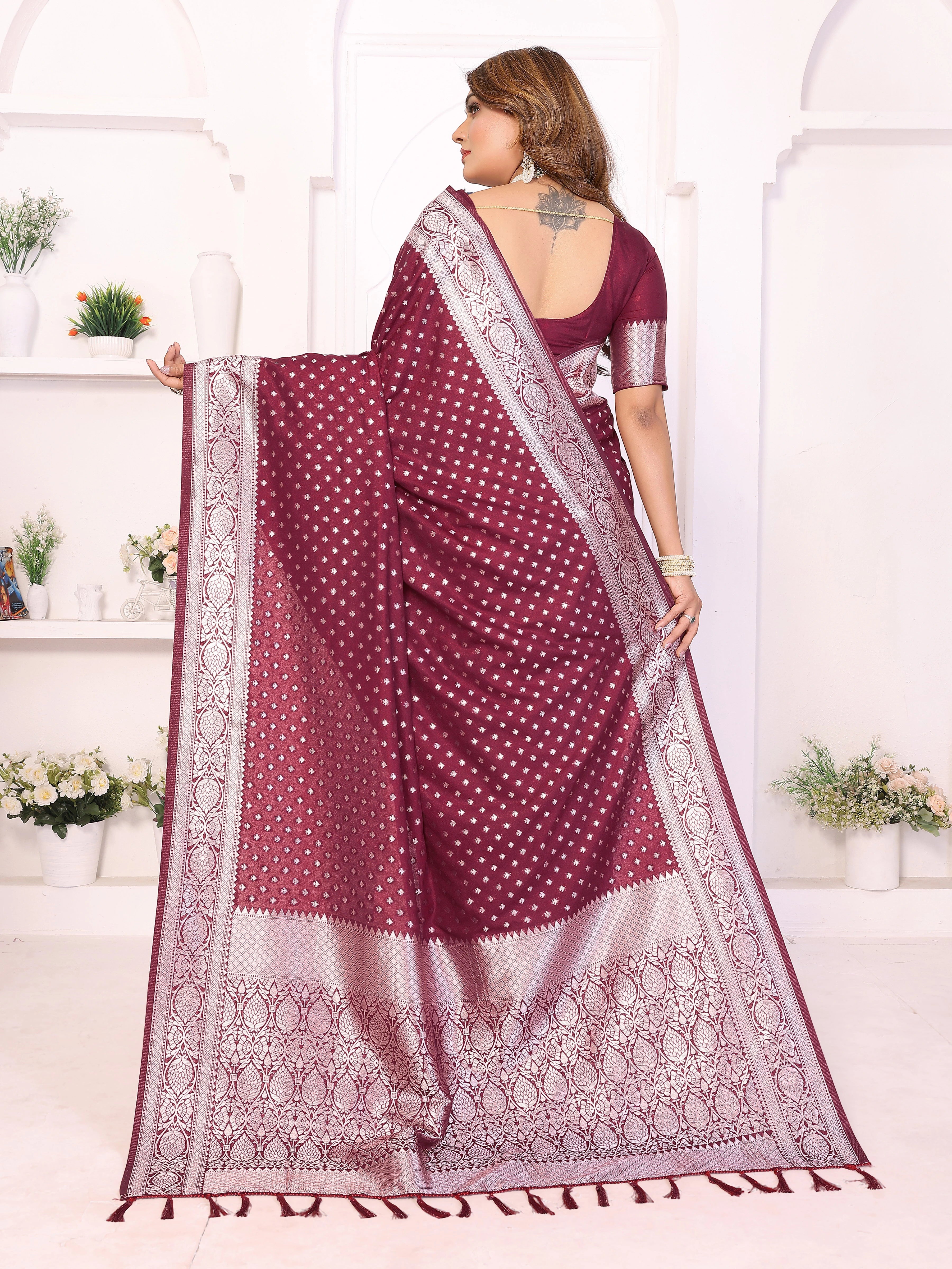 Woman wearing a maroon saree with white patterns in a bright room.