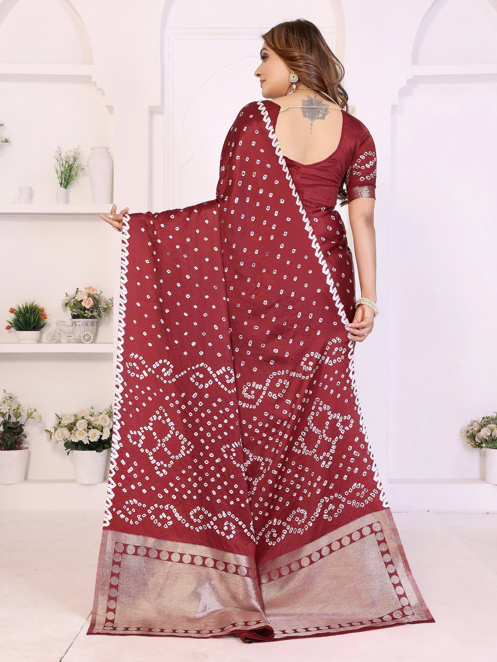 Woman wearing a maroon saree with white patterns in a minimalistic setting