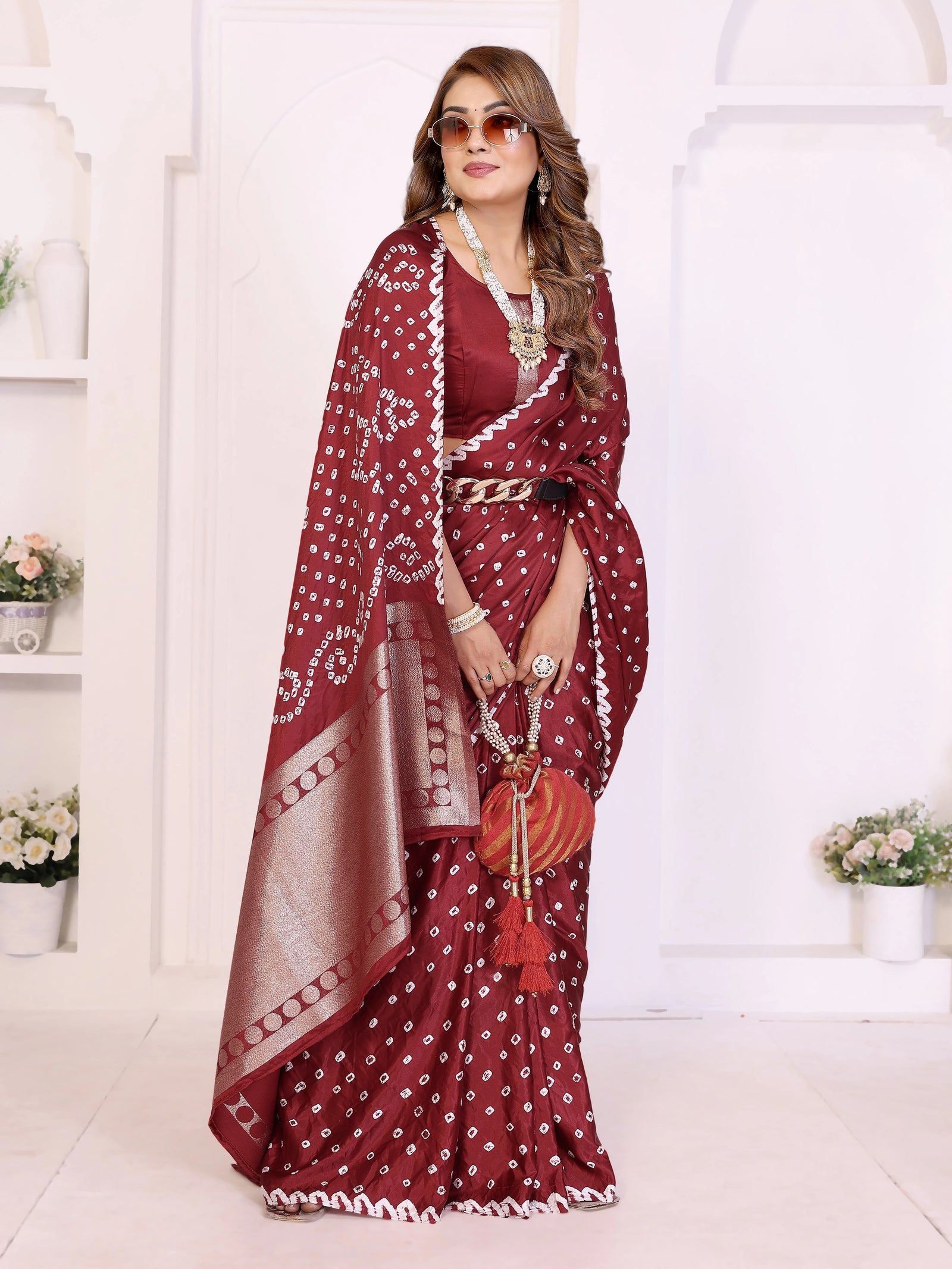 Woman in a maroon saree with white patterns standing in a white room.