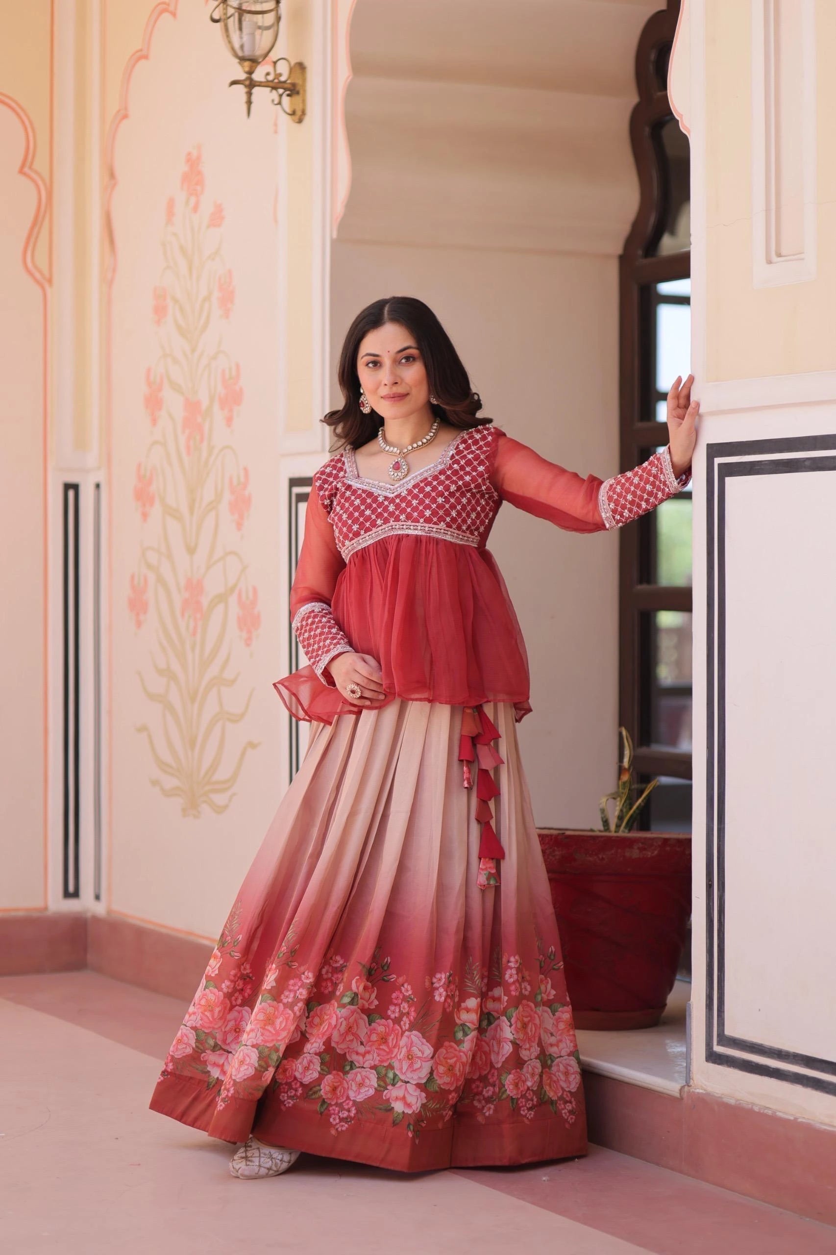 Woman in a red and white traditional outfit with floral design indoors.
