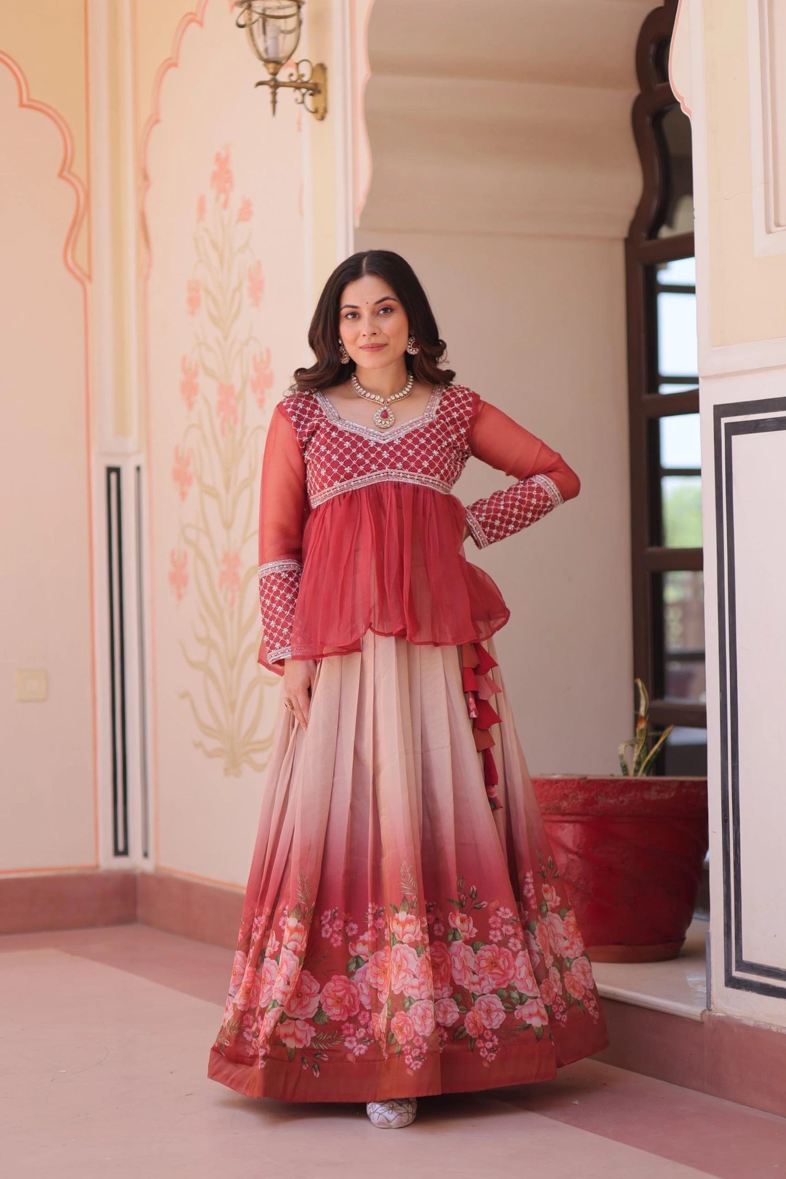 Woman in a red and white traditional outfit standing in an ornate room.