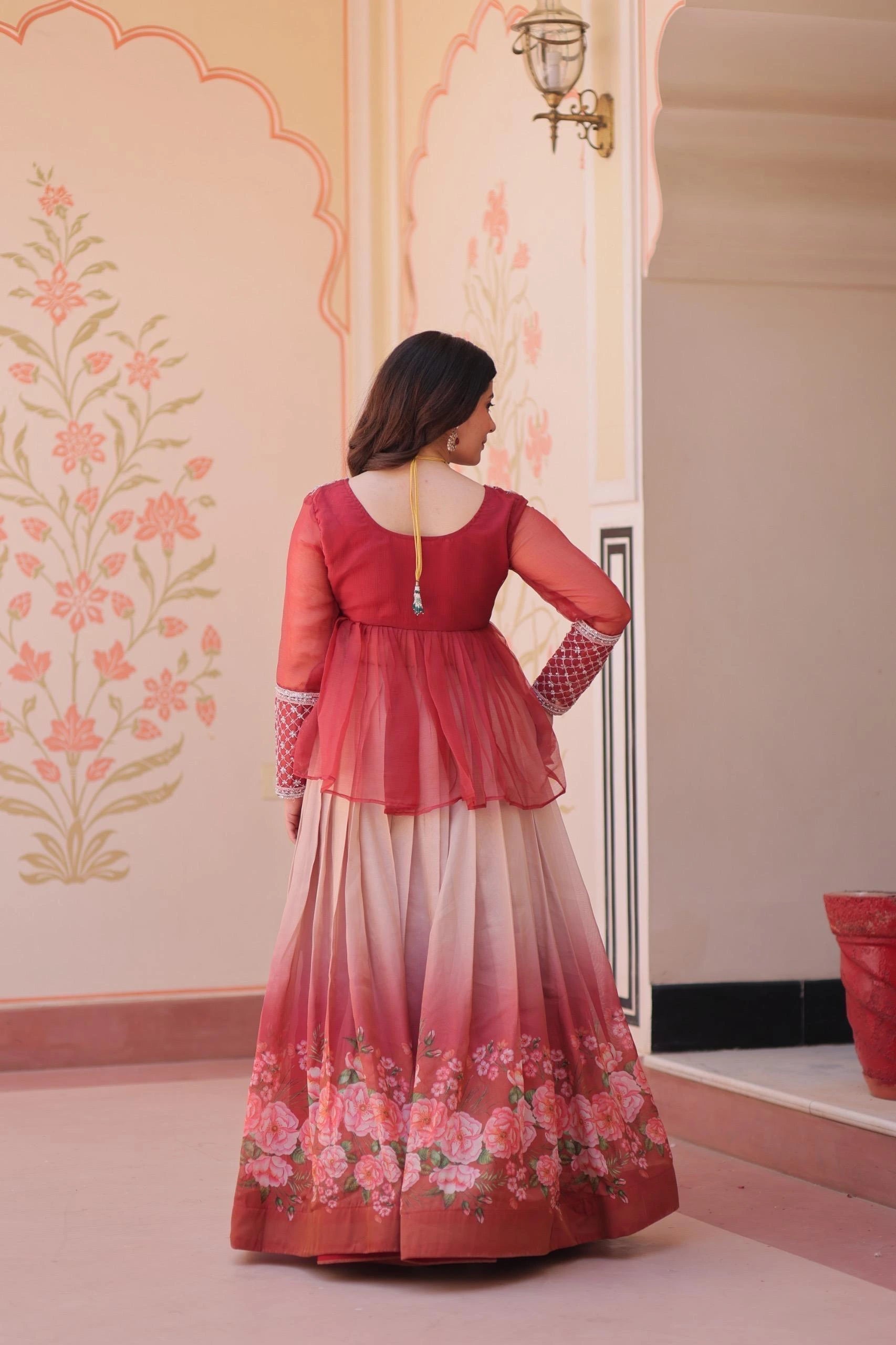 Woman in a red and white traditional outfit with floral patterns in a decorated room.