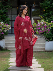 Woman in a red traditional outfit standing outdoors with flowers and steps in the background