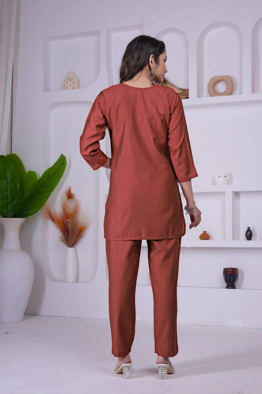 Woman wearing a rust-colored outfit standing in a minimalistic room with white walls and shelves.