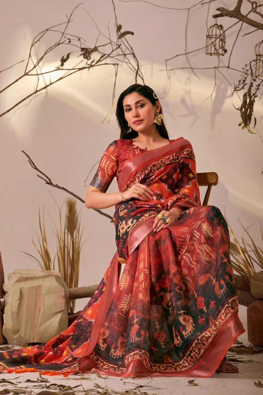 Woman in a red and black saree sitting on a chair with a neutral background