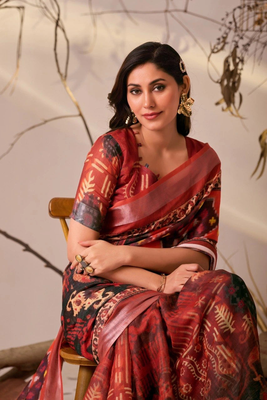 Woman in a red and black saree sitting on a chair with a neutral background