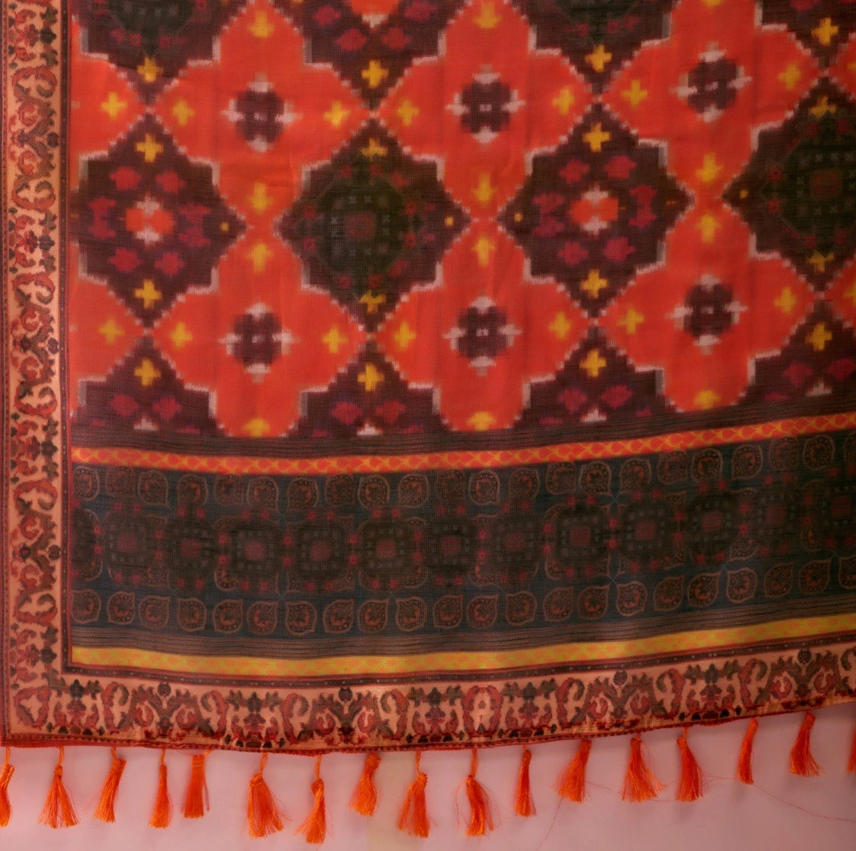 Decorative fabric with intricate patterns and tassels on a white background