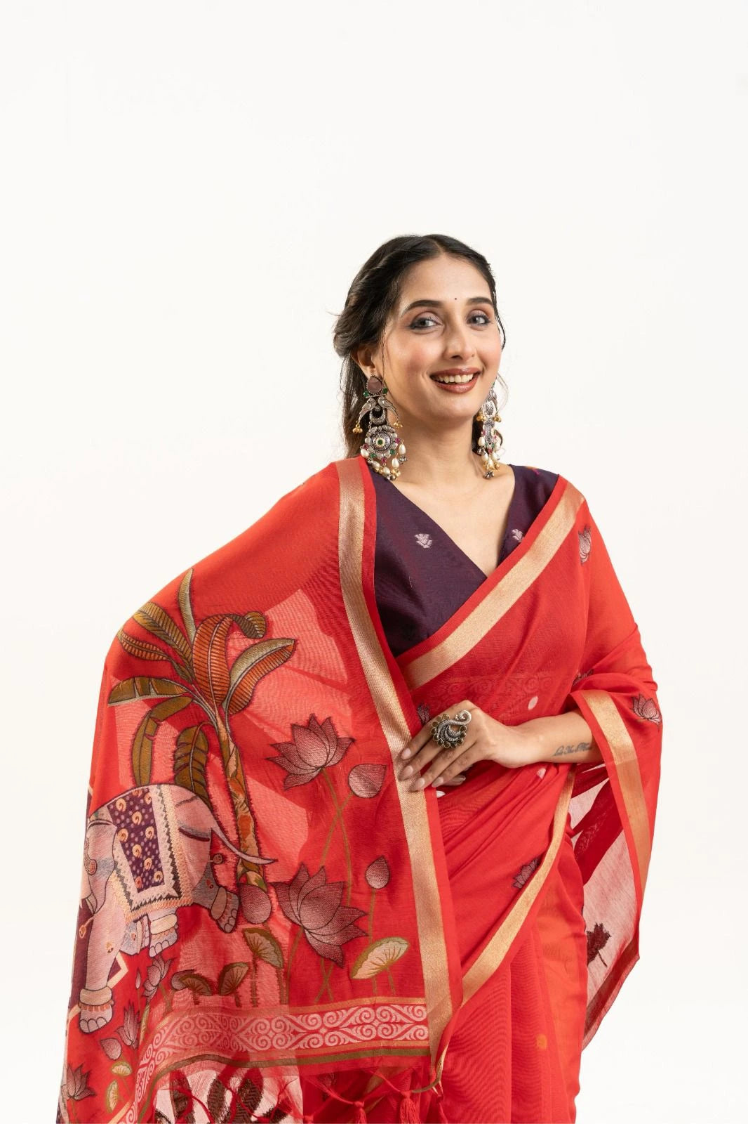 Woman wearing a red saree with floral patterns on a white background