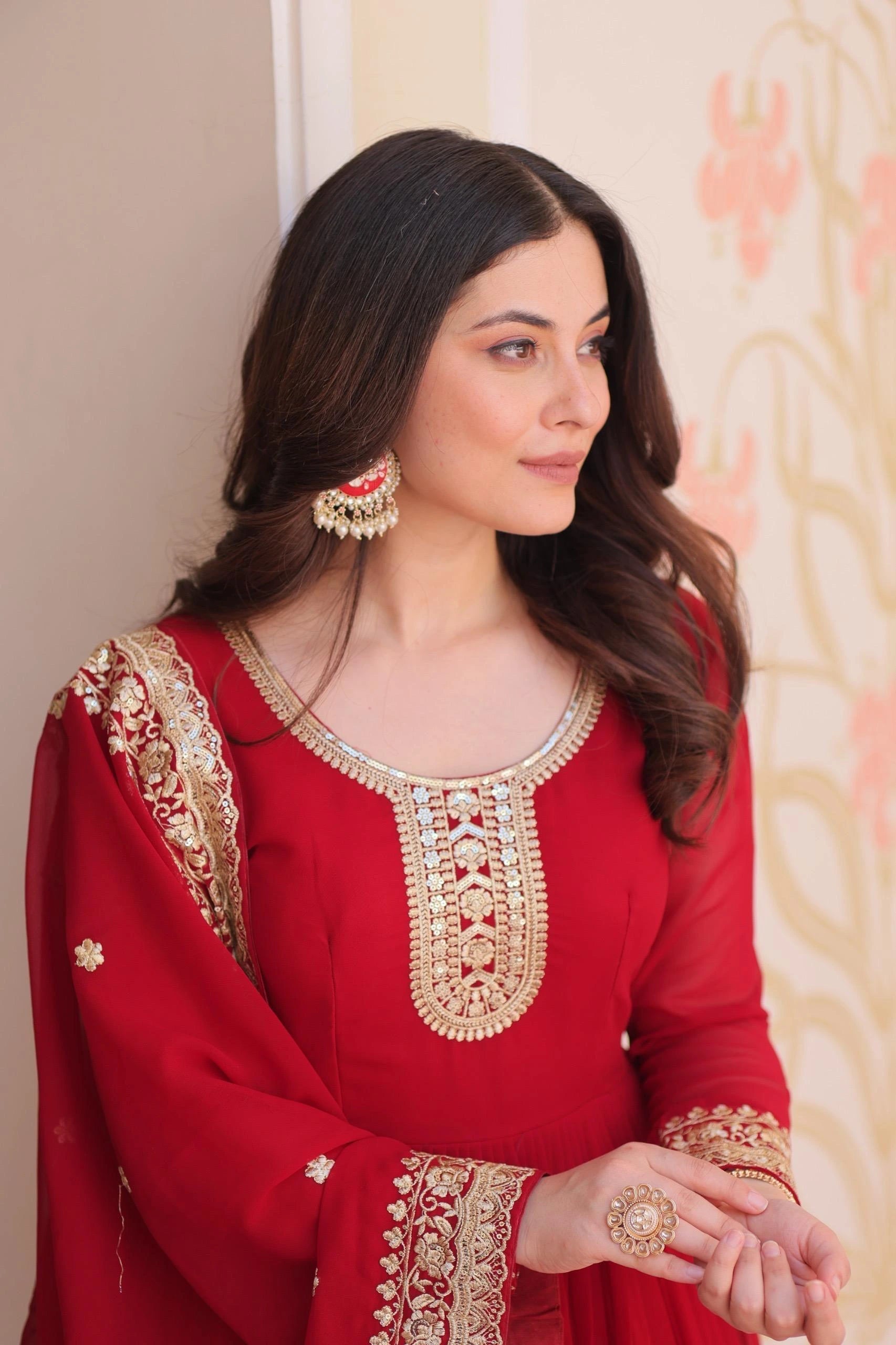Woman wearing a red embroidered traditional outfit with gold details.