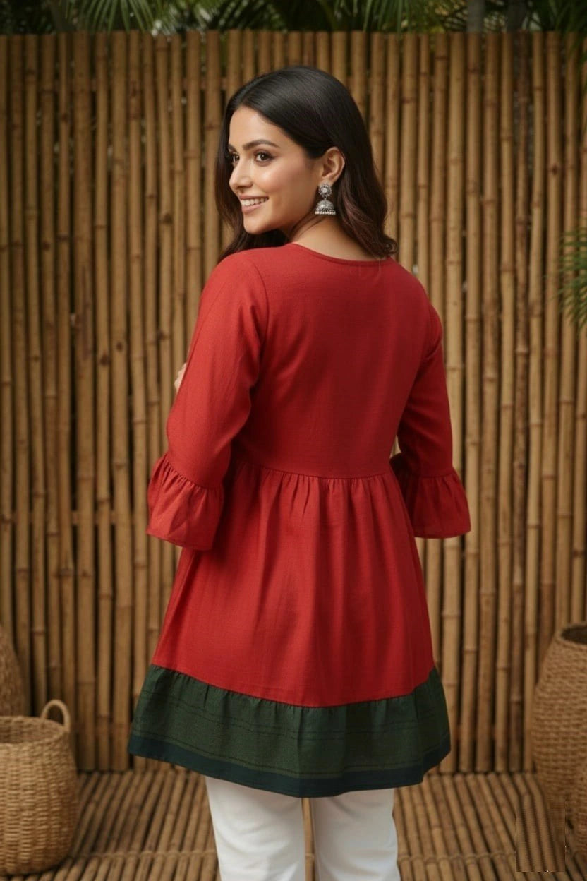 Woman wearing a red and green dress with a bamboo wall background