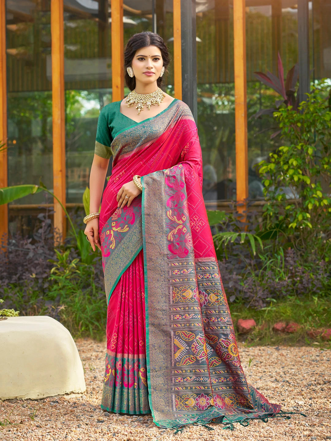 Woman wearing a pink saree with a patterned border outdoors.