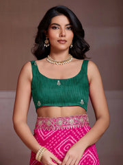 Woman wearing a green blouse and pink skirt with jewelry against a brown background