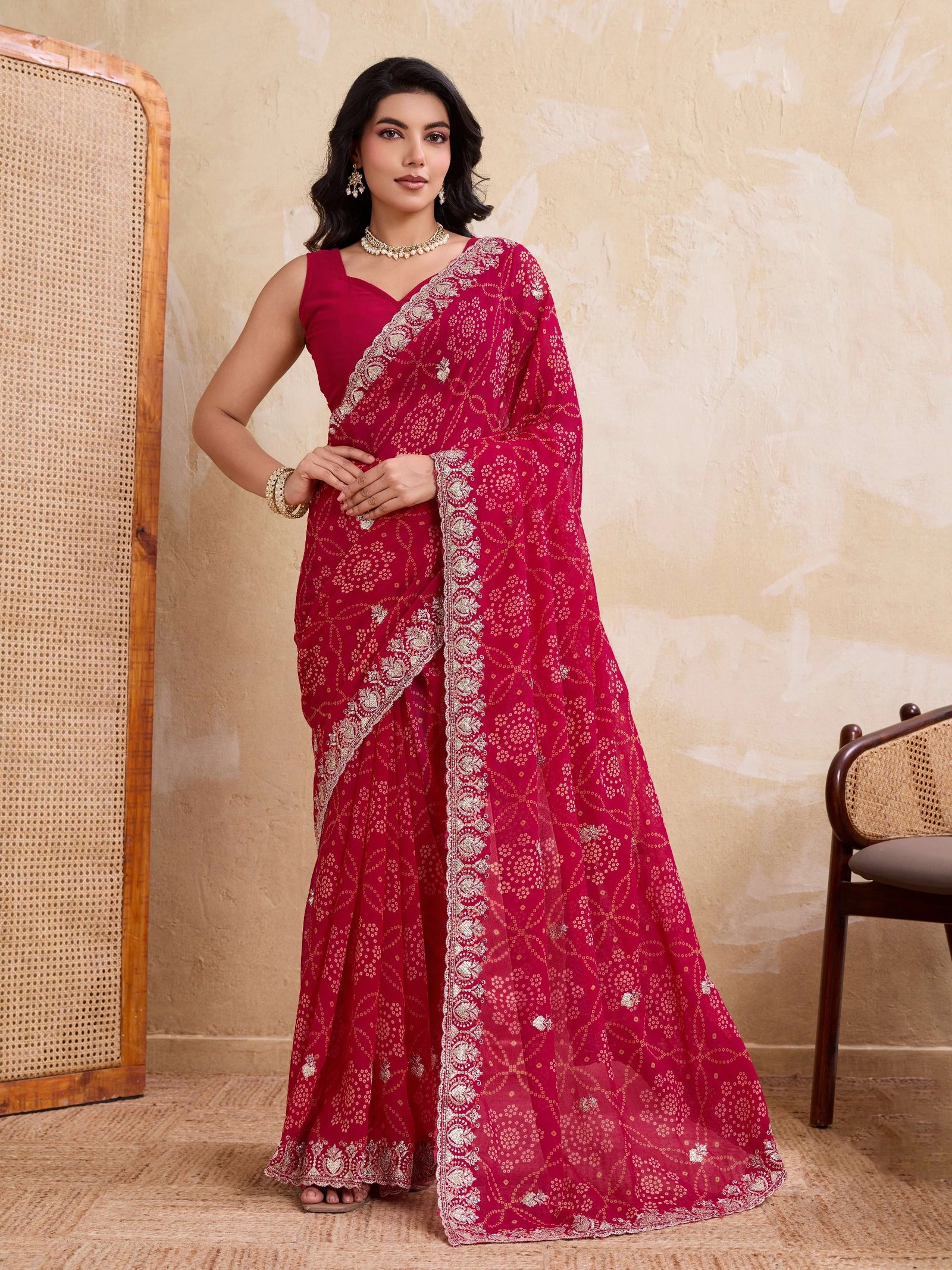 Woman wearing a red saree with white patterns in a room setting.