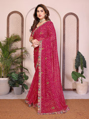 Woman wearing a pink saree with a patterned border in a decorated indoor setting.